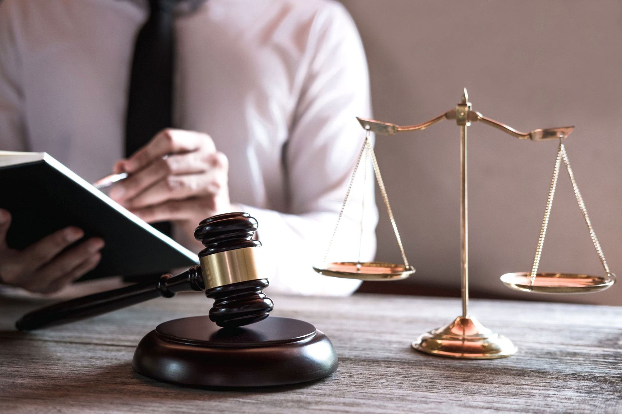 Scales of justice and a gavel on a wooden desk with documents under review